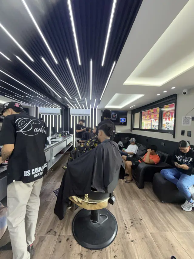 Interior de la barbería Los Caballeros en La Granja, Montería: techo de luces, sillas doradas y sala de espera