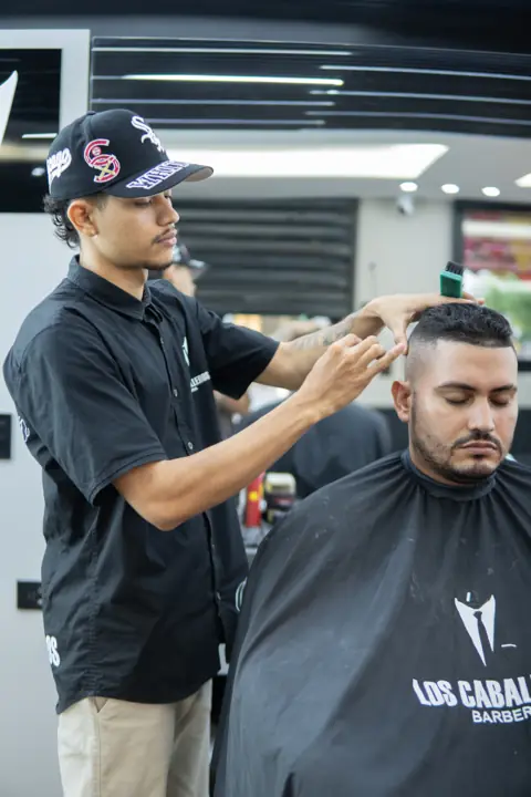 Barbero peinando un corte con degradado